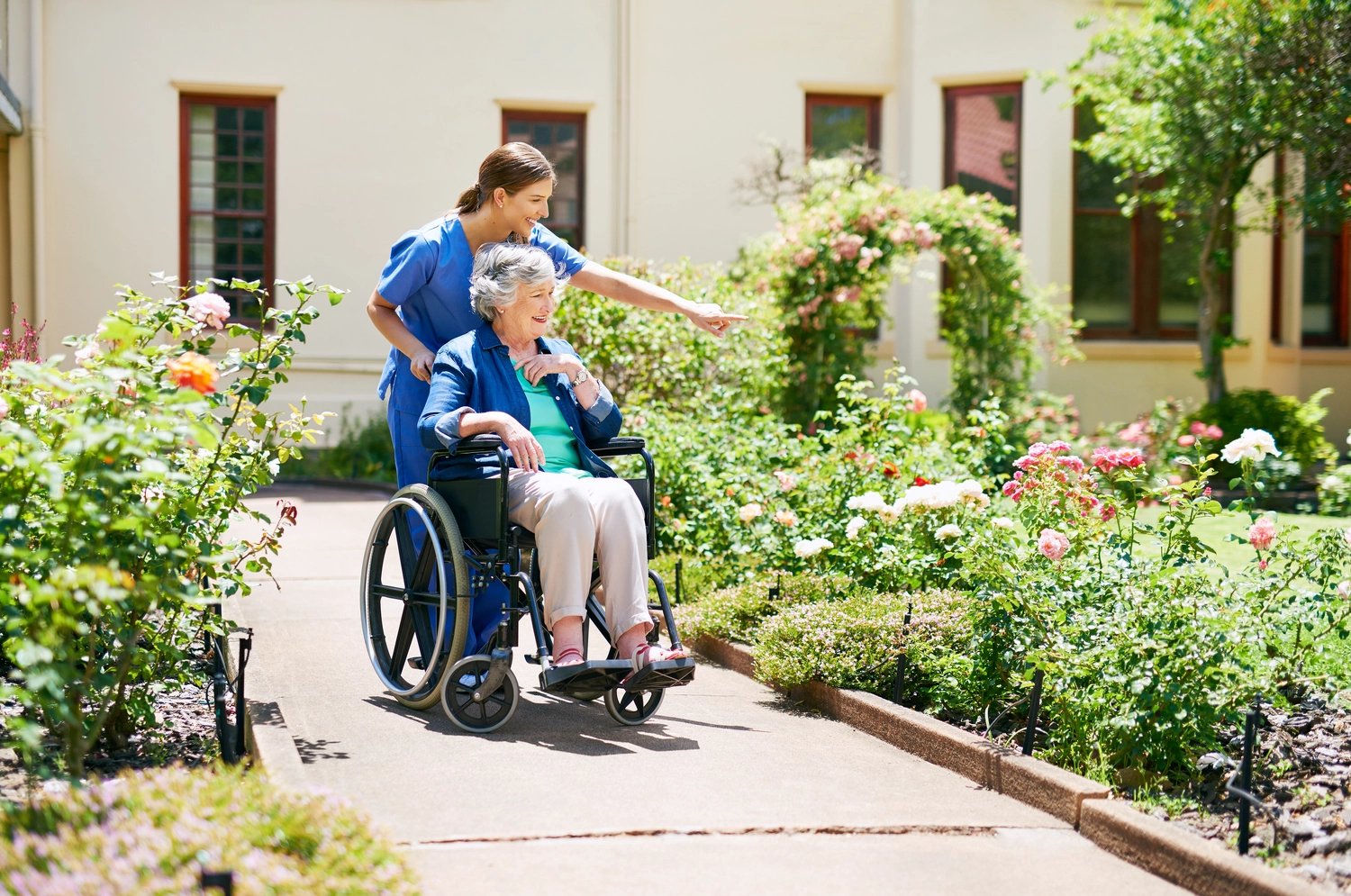 Sie benennt die Blumen. Aufnahme eines Bewohners und einer Pflegekraft im Garten des Seniorenheims.